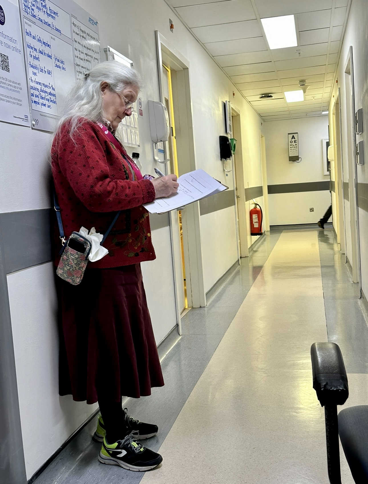 a picture of a volunteer standing in a hospital corridor taking notes