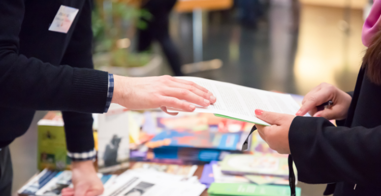 Picture of someone distributing leaflets to another person.