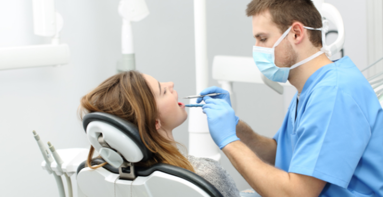 Male dentist doing a check up on a female patient in a clinic.