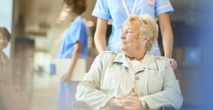 A nurse assisting a patient in a wheelchair in the hospital