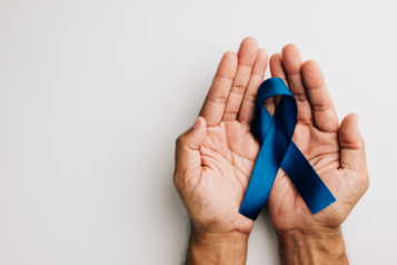 A hand holding a blue ribbon to symbolise men's health