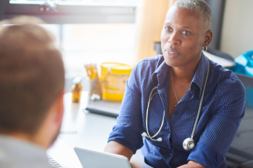 A doctor listening to a patient during their appointment.