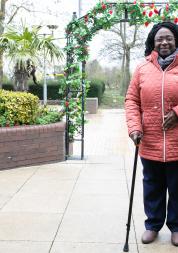 Woman walking with a stick across a courtyard